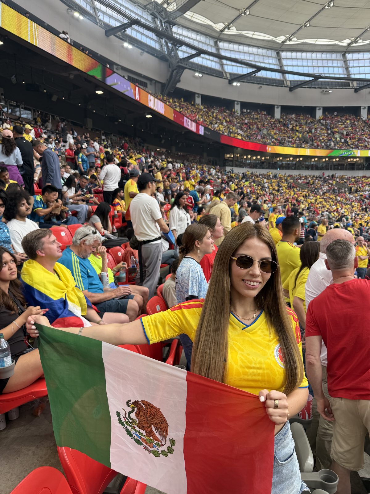 Isabella con la camiseta de México y la bandera en un estadio