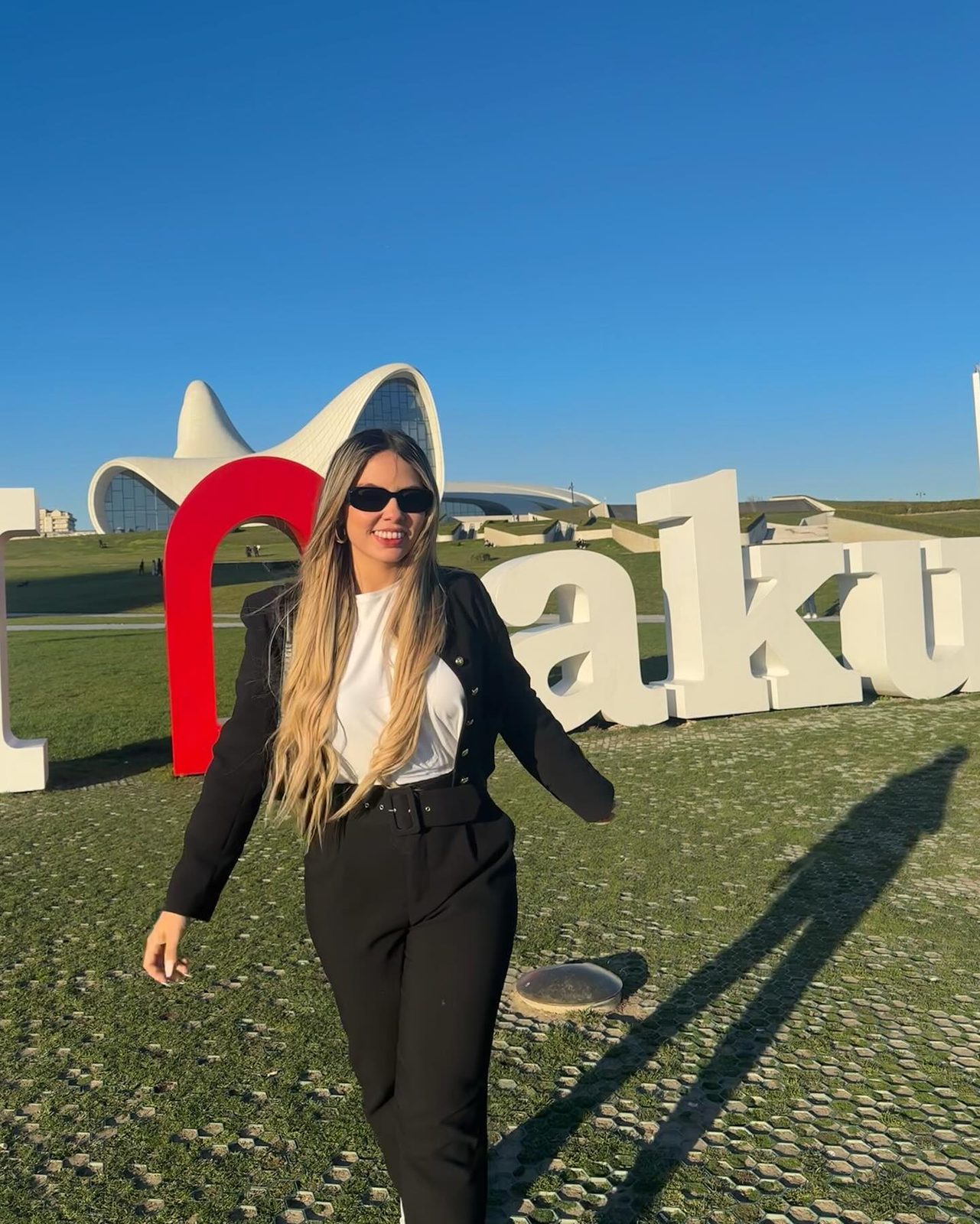 Isabella Duarte con traje negro y camisa blanca frente al letrero de Bakú